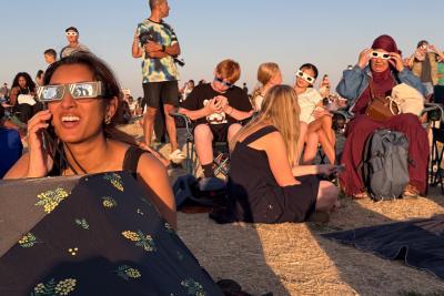 De nombreuses personnes sont assises sur la pelouse de la butte d'Orgemont pour admirer l'éclipse, lunettes de protection sur les yeux. - Enlarge image 1 of 6, modal window